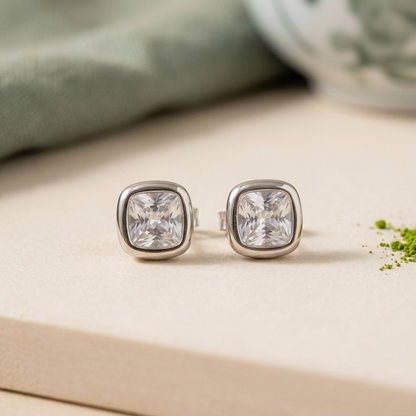 Aretes plateados de piedra clara sobre fondo marfil con un toque sutil de matcha
