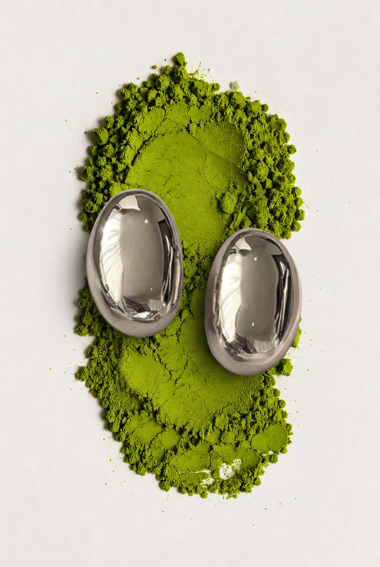 Aretes ovalados sobre polvo de matcha, fotografía editorial.