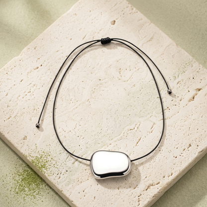 Collar Sienna sobre piedra clara con un toque de polvo verde matcha.