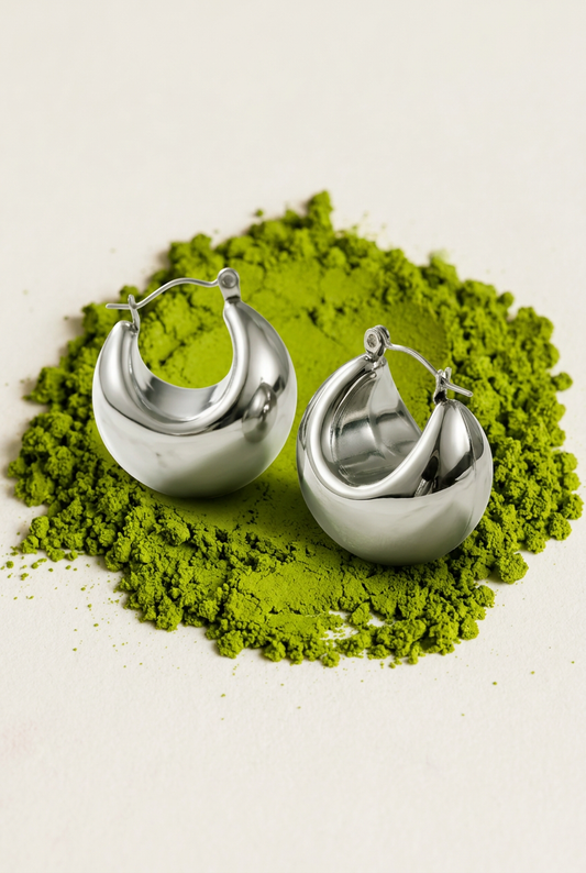 Aretes de aro sobre polvo de matcha, fotografía editorial.
